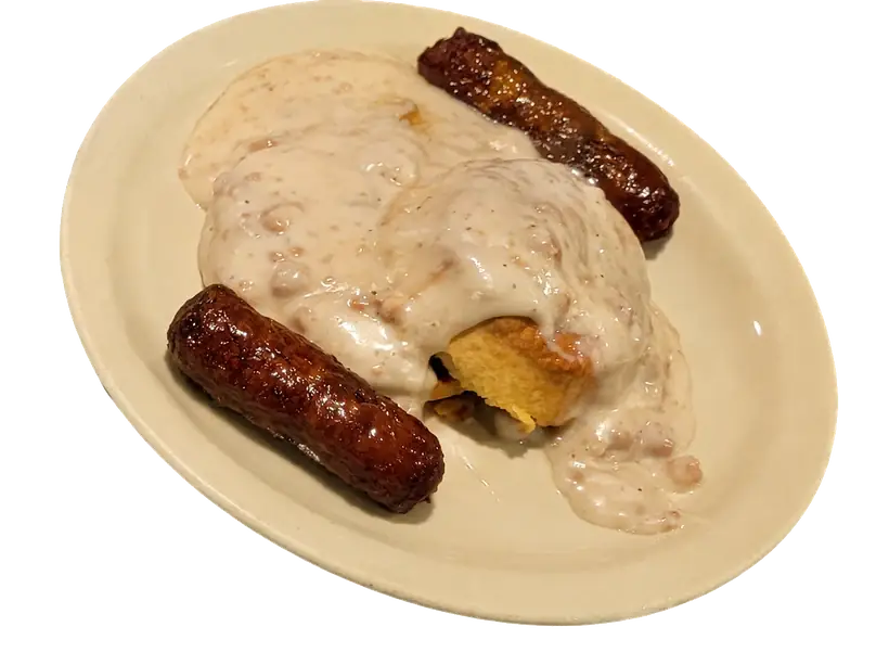 Biscuits covered in sausage gravy with breakfast sausage on a plate