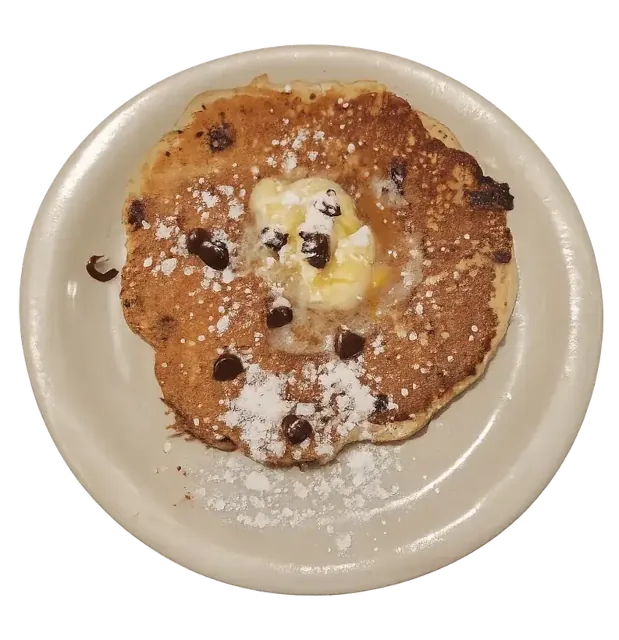 Chocolate chip pancake on a plate with powdered sugar and butter